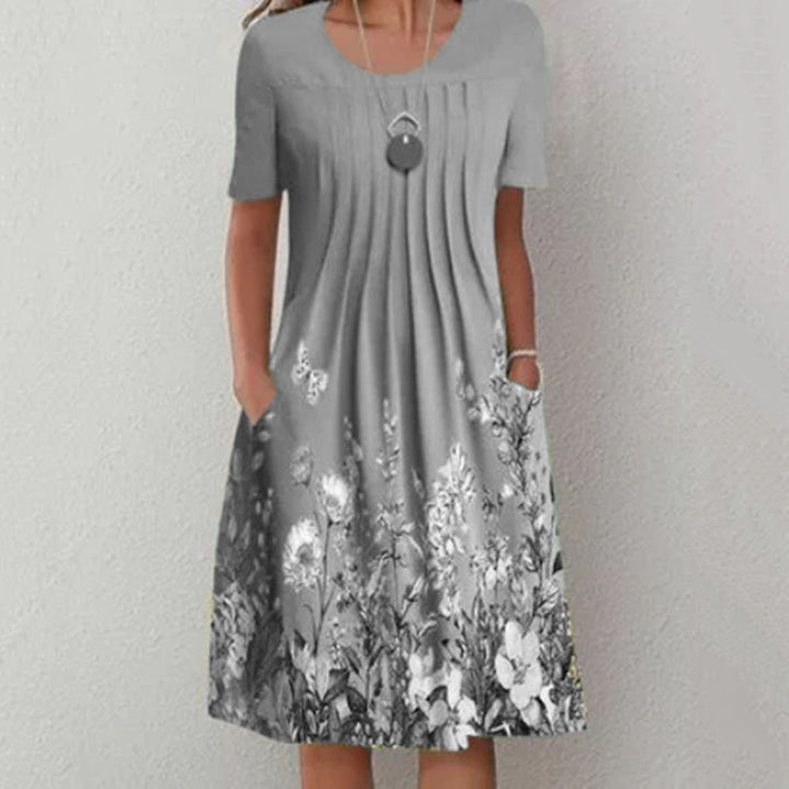 Damen Plissee Midi Kleid mit kurzen Ärmeln, seitlichen Taschen und floralem Saum – Élara