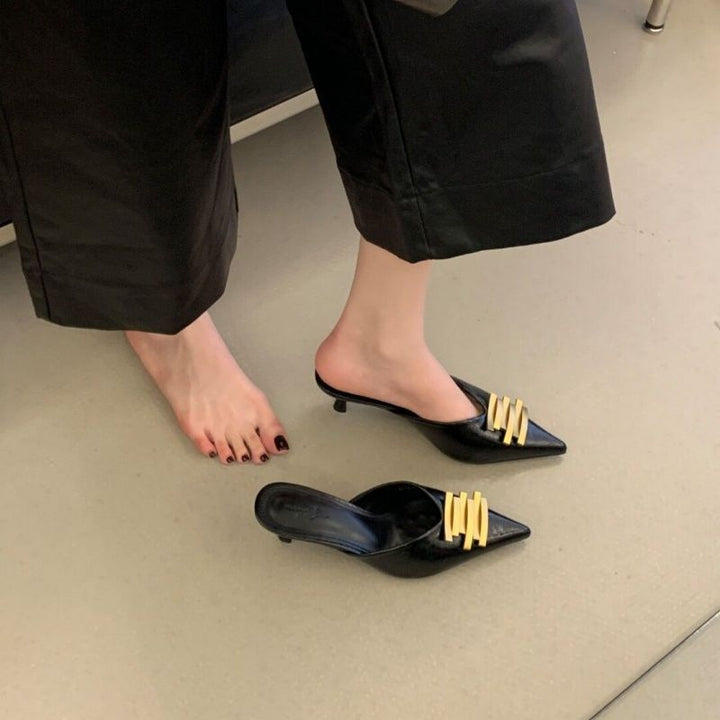 Damen Spitz zulaufende Lederoptik-Mules mit skulpturiertem Kitten‑Heel und goldener Wellenapplikation – Avérine